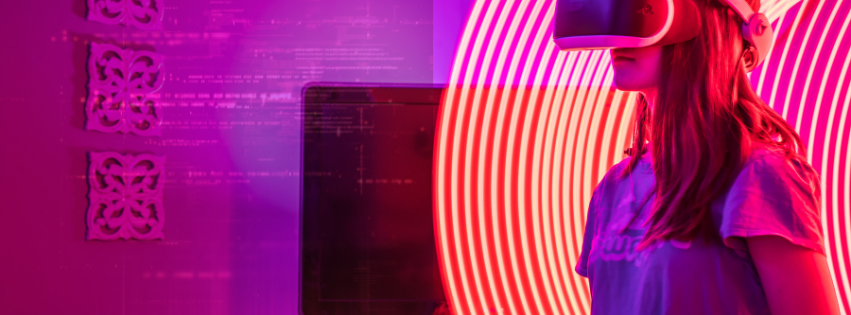 A woman wearing VR goggles stand in front of pink lights