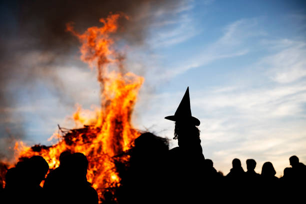 People silouetted against a dusky sky around a bonfire