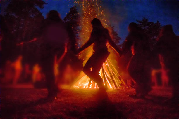 A group of people dancing around a bonfire at night