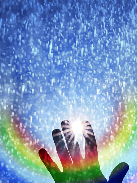 A hand reaching up to a rainbow during a rain storm