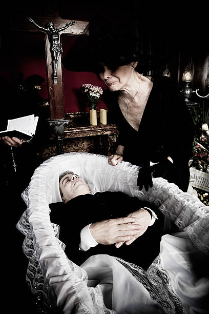 A grieving woman stands above a body in a coffin