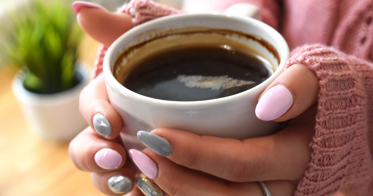 Two hands reverently holding a cup of coffee