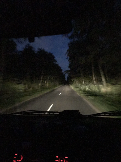 A car driving down a dark and deserted road