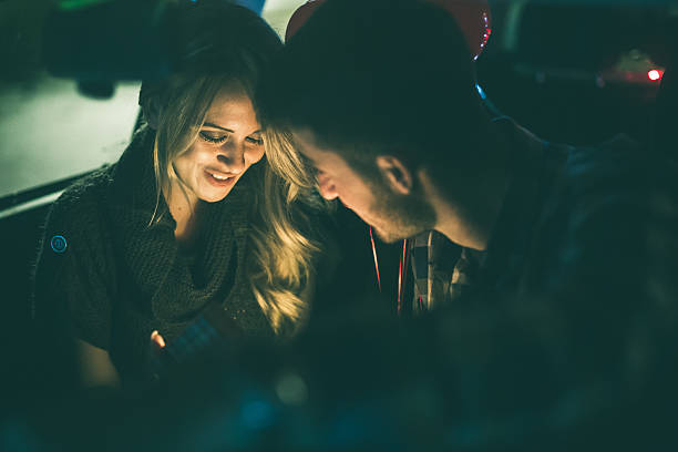 A young couple sitting together in a car at night