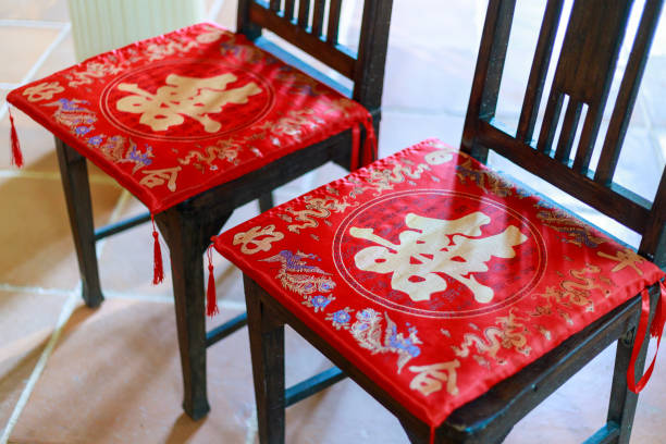 Two wooden chairs with red seat cusions with a chinese character on them