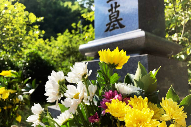A grave with flowers and kanji writing on the stone